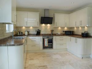 a kitchen with white cabinets and marble counter tops at Y Hendy Llaeth in Cyffic