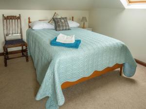 1 dormitorio con 1 cama con manta azul y silla en Middle Lodge en Mintlaw