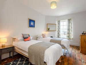 two beds in a room with white walls and wooden floors at Colveston Manor in Cranwich