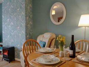 a dining room table with a fireplace and a mirror at Parkside Cottage in Frizington