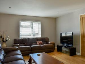 a living room with a couch and a flat screen tv at Hill Farm Cottage in Stretham
