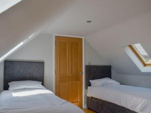 a bedroom with two beds and a wooden door at Hill Farm Cottage in Stretham