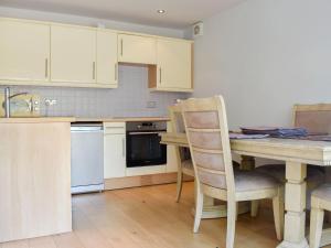una cucina con armadi bianchi, tavolo e sedie di Hill Farm Cottage a Stretham
