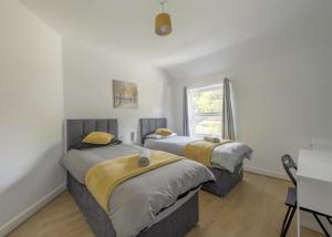 two beds in a room with a window at Birmingham Contractor House sleeps 8 Private Garden near M6 Motorway Business Wi-FI in Birmingham