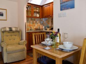 a kitchen with a wooden table and a chair at Heron Cottage in Lossiemouth