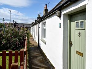 a row of white houses with a green door at Heron Cottage in Lossiemouth