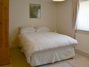 een slaapkamer met een bed met witte lakens en een raam bij Fairway Cottage- Uk11780 in Lucker