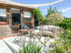 a patio with a table and chairs and flowers at Cenwulf Cottage in Winchcombe