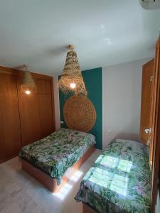 a bedroom with two beds and a chandelier at Encanto. Céntrico tríplex cerca de la Corredera y casco antiguo. in Córdoba +24 photos