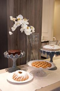 a table with three cakes and a vase with flowers at Hotel Carla in Levanto
