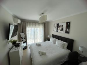 Un dormitorio con una cama blanca con dos velas. en Rocha Prime - Standing apartment T3 en Portimão