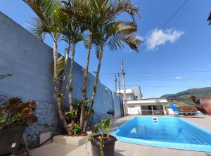 una piscina con palmeras junto a un edificio en Casa com vista para o Cristo e piscina, en Encantado