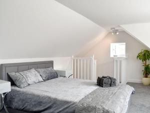 a white bedroom with a bed and a plant at Newhope in Winchelsea