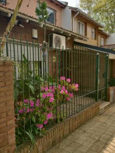 una cerca con flores rosas delante de una casa en Casa ideal para familia, a minutos de Buenos Aires en Martínez