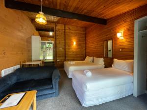 ロトルアにあるLakes Lodge Okatainaのベッド2台とソファが備わるホテルルームです。