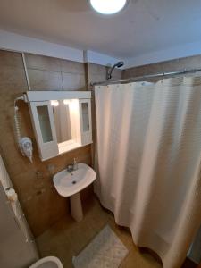 baño con cortina de ducha blanca y lavamanos en Paraná Confort en Paraná