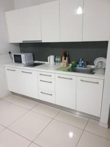 eine weiße Küche mit Spüle und Mikrowelle in der Unterkunft ICity Homestay Konvokesyen Dan Percutian Shah Alam 1R 1Q 1S 1Sofabed in Shah Alam