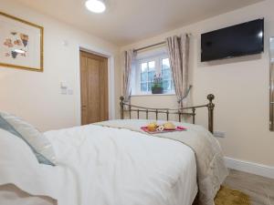 a bedroom with a bed with a tv on the wall at Kingfisher Cottage in Wainfleet All Saints