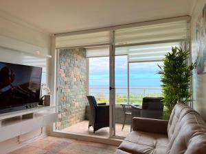 a living room with a couch and a large glass window at Reñaca Frente al Mar in Viña del Mar