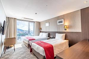 a hotel room with two beds and a large window at Ramada by Wyndham Jeju City Hall in Jeju +144 photos