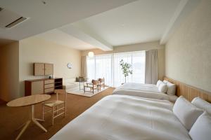 a hotel room with two beds and a desk at Hotel Lepo Chahal in Matsuyama