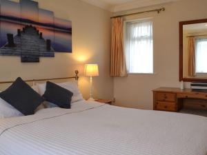 1 dormitorio con 1 cama blanca grande y espejo en The Cottage At Boscobel en Brockenhurst