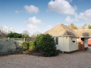 una casa blanca con valla y entrada en The Cottage At Boscobel en Brockenhurst