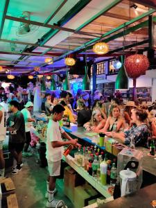 a group of people at a bar with people sitting at tables at Gili Beach Bum Hostel in Gili Trawangan