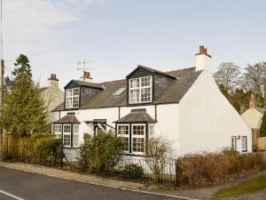a white house with a black roof at Burnbrae Cottage in Bridgend of Lintrathen