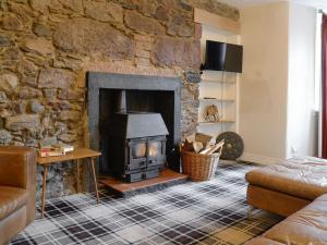 a living room with a stone wall with a fireplace at Burnbrae Cottage in Bridgend of Lintrathen