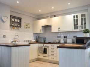 a kitchen with white cabinets and a counter top at Little Vines in Strensham