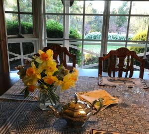 a table with a vase of yellow flowers on it at Hawk's Nest Bed & Breakfast in Bathurst