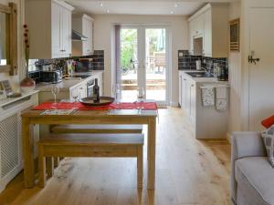 a kitchen with a wooden table in the middle at Beech Tree Cottage in Horning