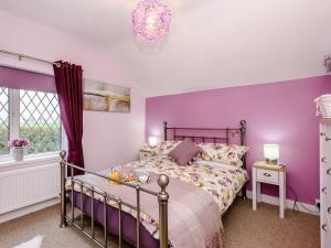 a purple bedroom with a bed and a chandelier at Beech Tree Cottage in Horning
