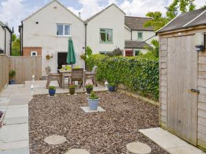 a garden with a wooden fence and a patio at Beech Tree Cottage in Horning