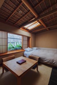 京都市にある旅館 元奈古のベッド2台、テーブル、窓が備わる客室です。
