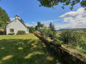 a white house with a stone wall in the yard at Inch Alla in Achany