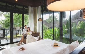 une mariée et un marié assis dans une pièce avec de grandes fenêtres dans l'établissement The Vijitt Resort Phuket - SHA Extra Plus, à Rawai Beach