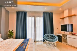 ein Schlafzimmer mit einem Bett, einem Stuhl und einem TV in der Unterkunft HANZ Light House Hotel & Apartment in Hanoi