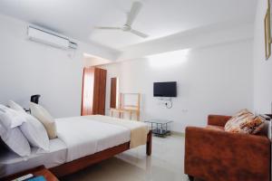 a bedroom with a bed and a couch and a tv at Achates Corporate Services in Bangalore