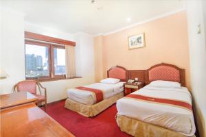 um quarto de hotel com duas camas e uma secretária e uma janela em Hotel Bisanta Bidakara Tunjungan em Surabaya