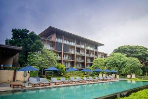 a hotel with chairs and umbrellas next to a pool at Khaoyai Luxury Pool Penthouse at ATTA in Pak Chong