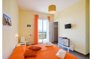 een slaapkamer met een oranje bed en een televisie bij Cozy Home In Scicli With Outdoor Swimming Pool in Scicli