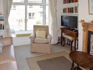 uma sala de estar com uma cadeira e uma televisão em Cranmere em Salcombe