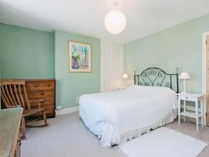 um quarto com uma grande cama branca e uma cadeira em Cranmere em Salcombe