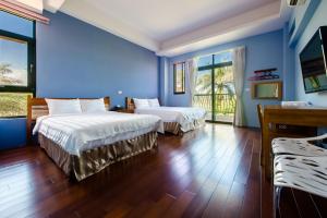 台東市的住宿－仲夏綠茵民宿，配有蓝色墙壁和木地板的客房中的两张床
