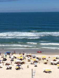 a group of people on a beach with umbrellas at Apartamento Pitangueiras in Guarujá