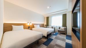 a hotel room with two beds and a tv at JR-East Hotel Mets Yokohama Sakuragicho in Yokohama