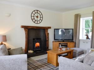 a living room with a fireplace and a tv at Belstane Cottage in Straiton