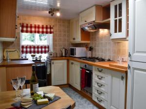 a kitchen with white cabinets and a table with wine glasses at Belstane Cottage in Straiton